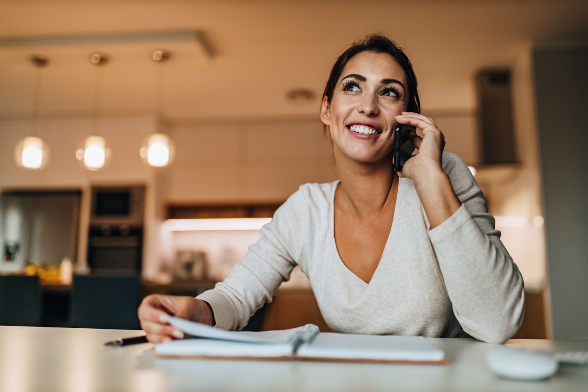 Femme souriante au téléphone, écrivant dans un carnet