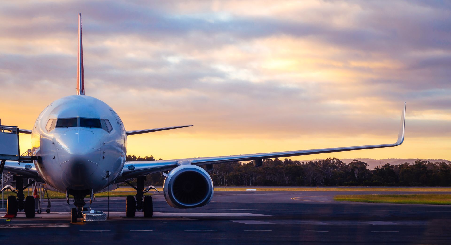 Avion stationné sur la piste au coucher du soleil, vue de face avec ciel illuminé.