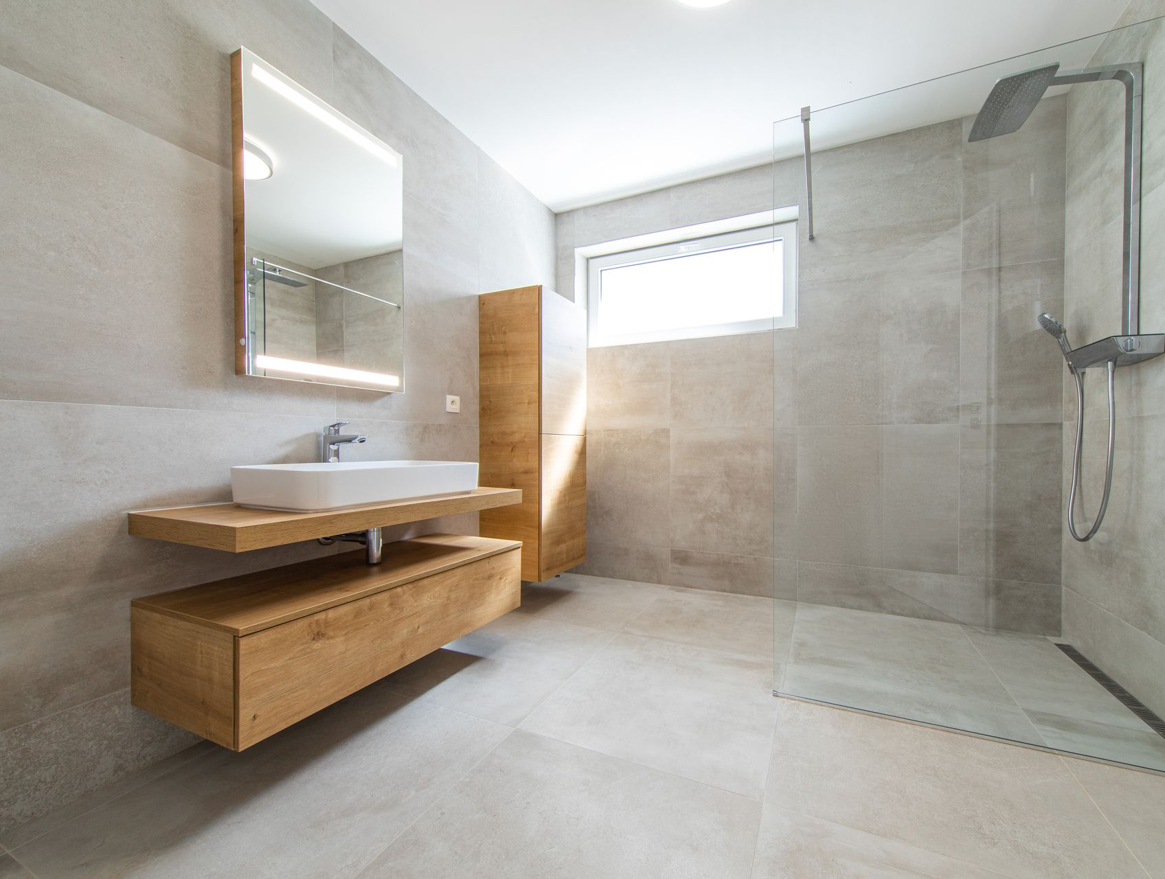 Salle de bains moderne avec meuble-lavabo suspendu en bois, miroir et douche à l'italienne en verre.