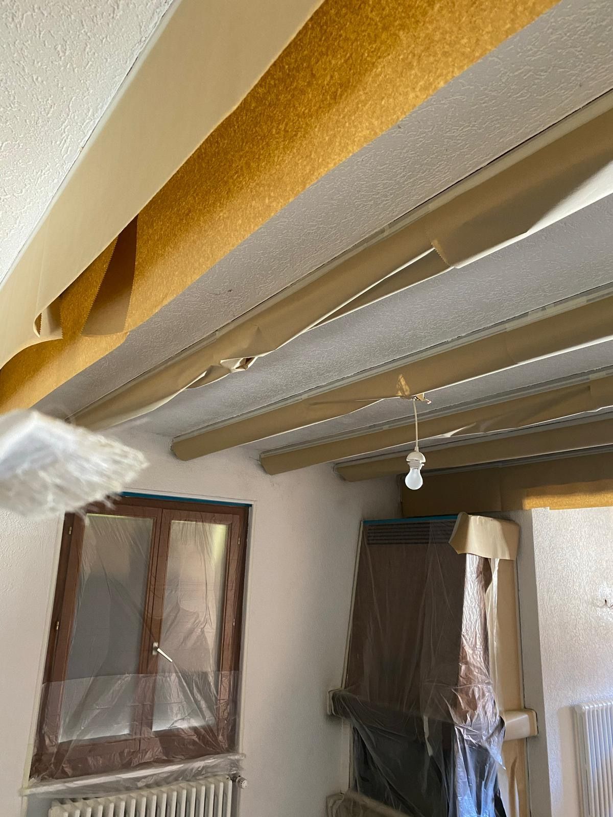 Une pièce avec un plafond en cours de peinture et une fenêtre.