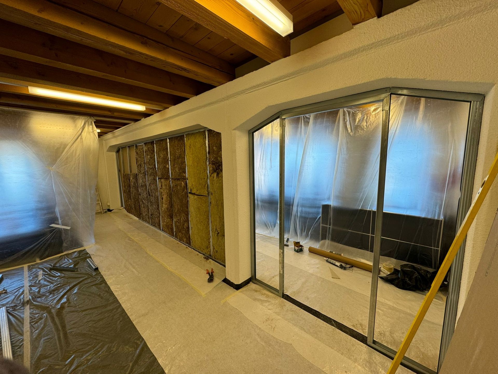 Une pièce avec des portes coulissantes en verre et un plafond en bois est en cours de rénovation.
