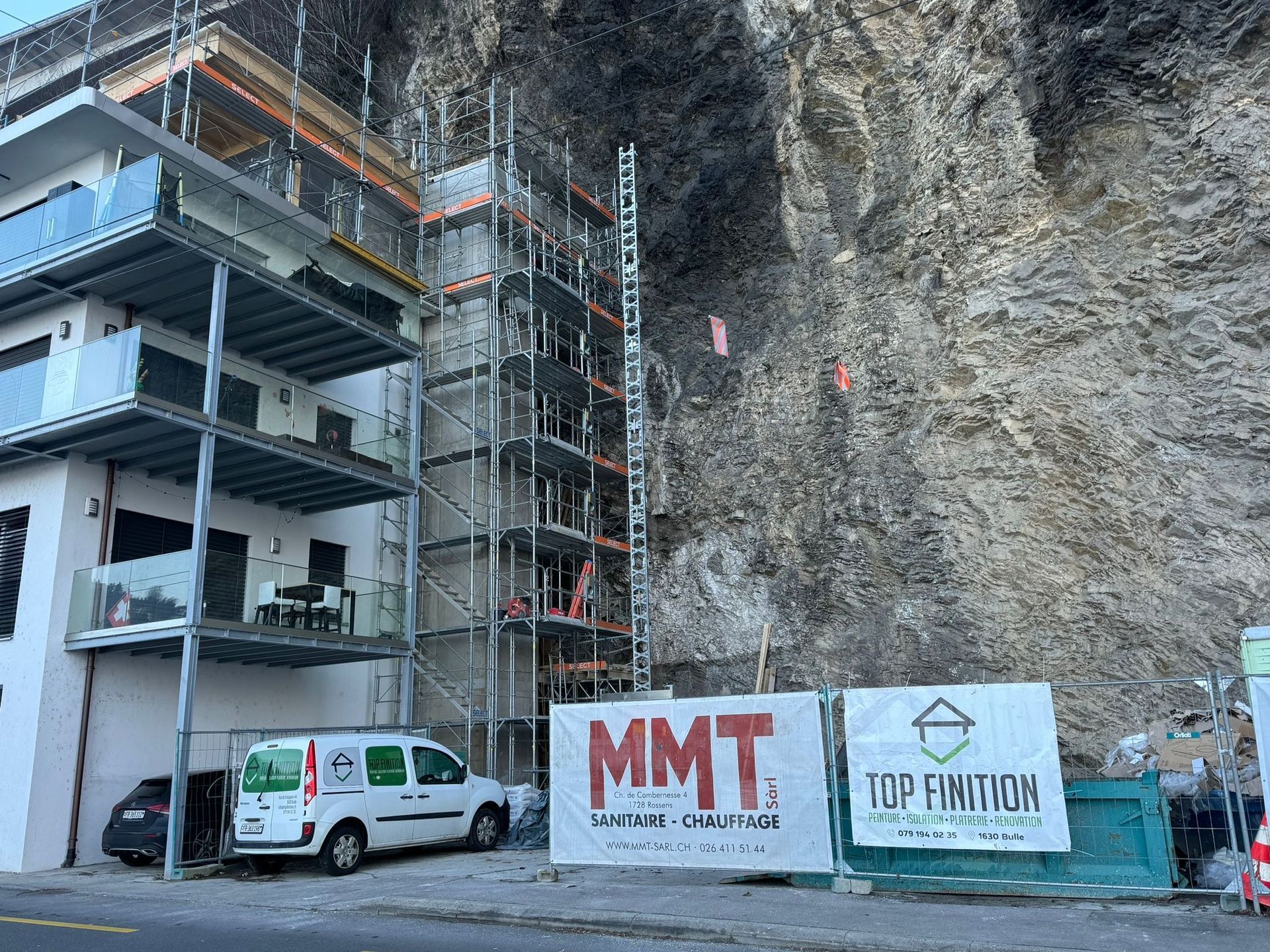 Une camionnette blanche est garée devant un immeuble en construction.
