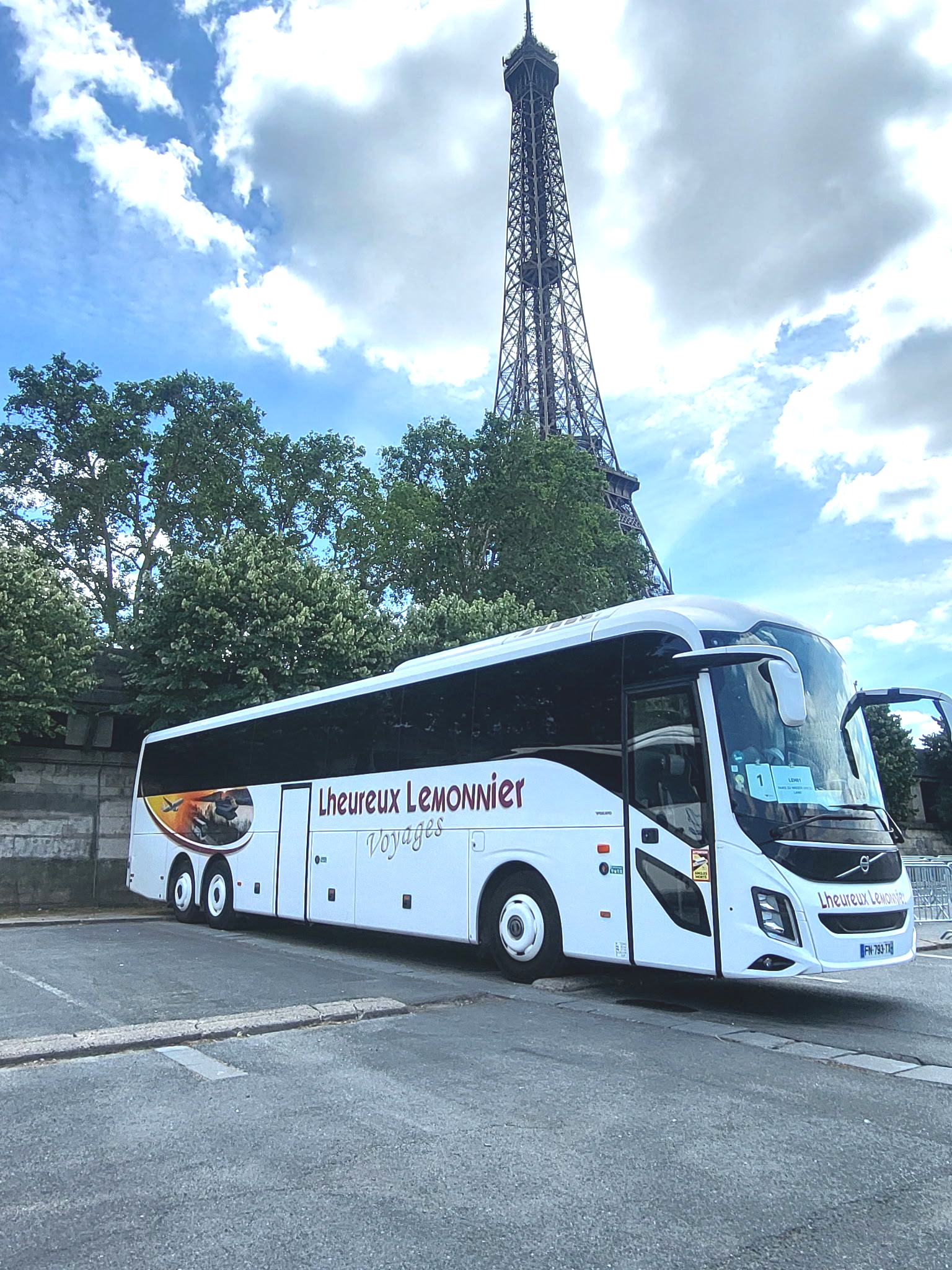 Un autobus de passagers circulant sur une route dégagée au coucher du soleil, avec des montagnes se détachant en arrière-plan.