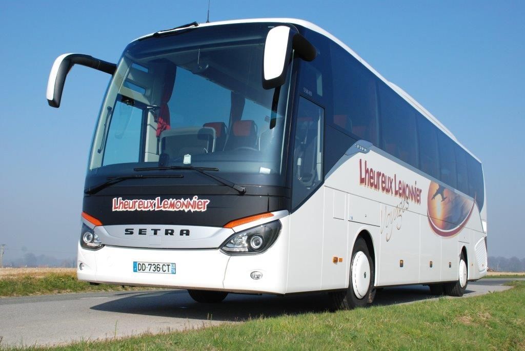 Un bus touristique blanc Setra garé sur le bord d'une route, se détachant sur un ciel bleu azur.