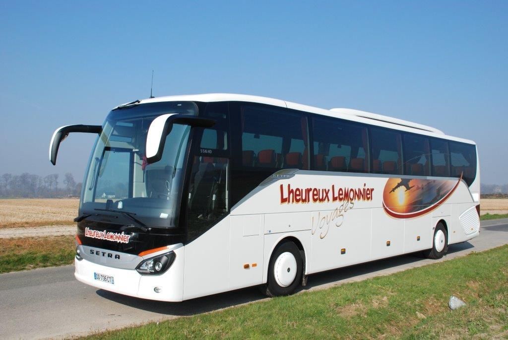 Un autocar Setra blanc, portant l'inscription « Lheureux Langwiser », circule sur une route de campagne sous un ciel bleu azur.
