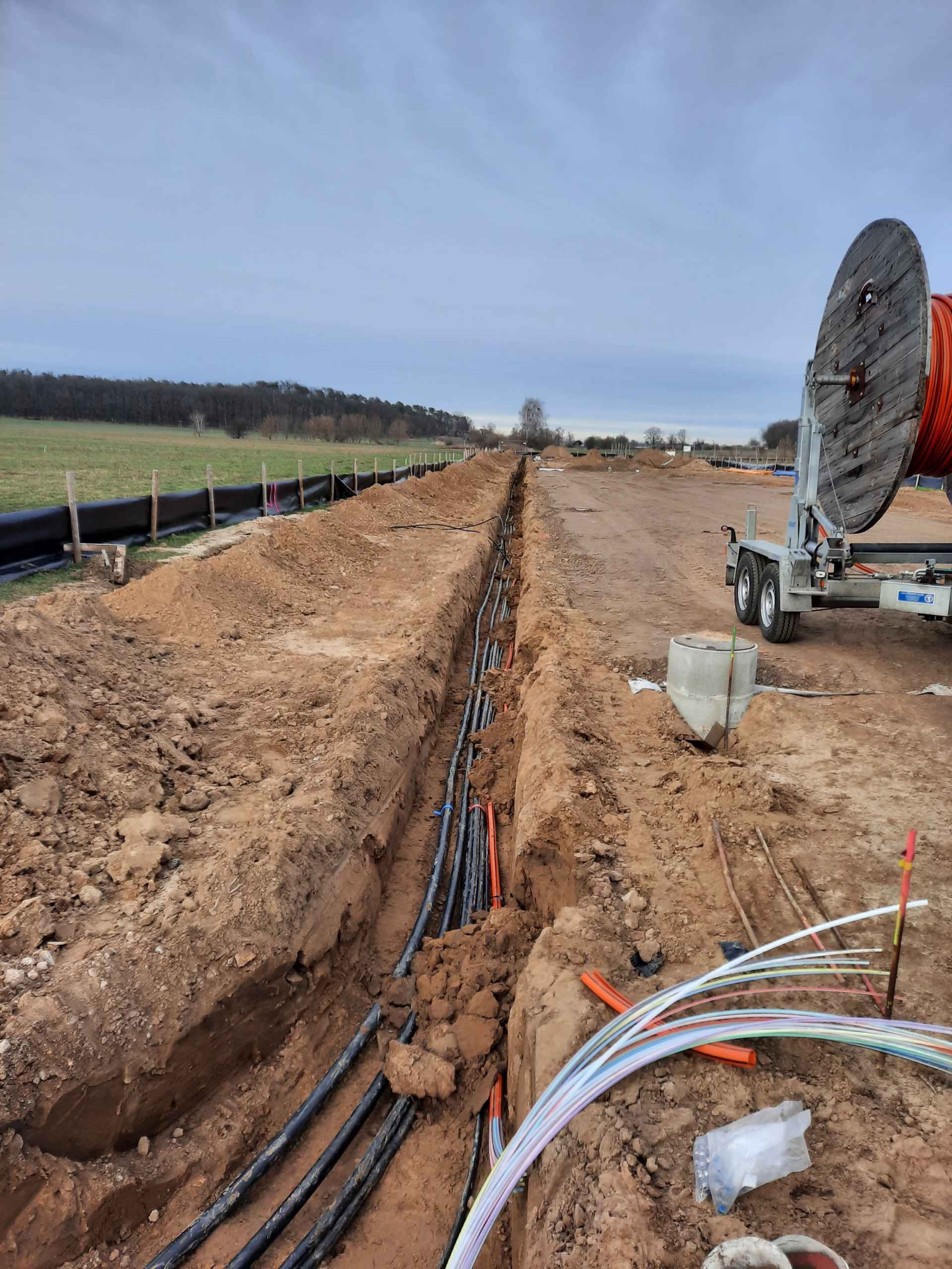 In einem Graben liegt ein Bündel Kabel im Dreck.
