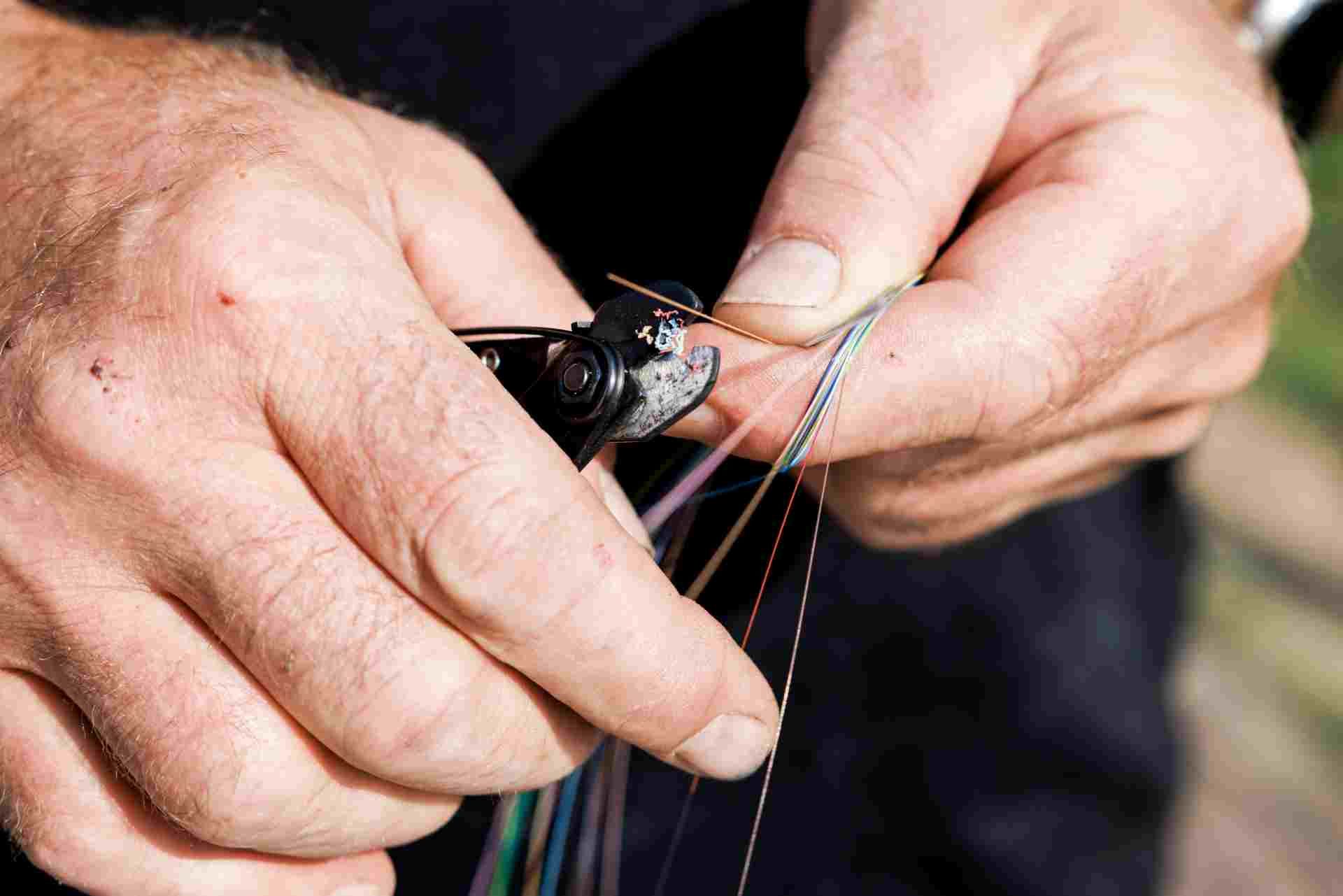 Ein Mann schneidet mit einer Zange einen Draht durch.