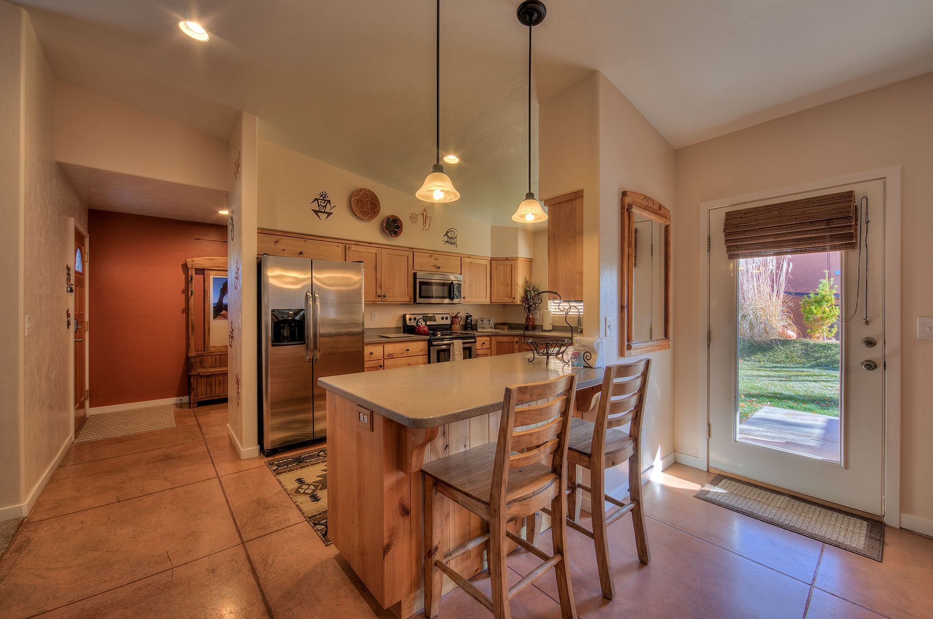 Moab, Utah Oleander Place vacation rental Kitchen with light wood cabinets, stainless steel appliances. Door to backyard.