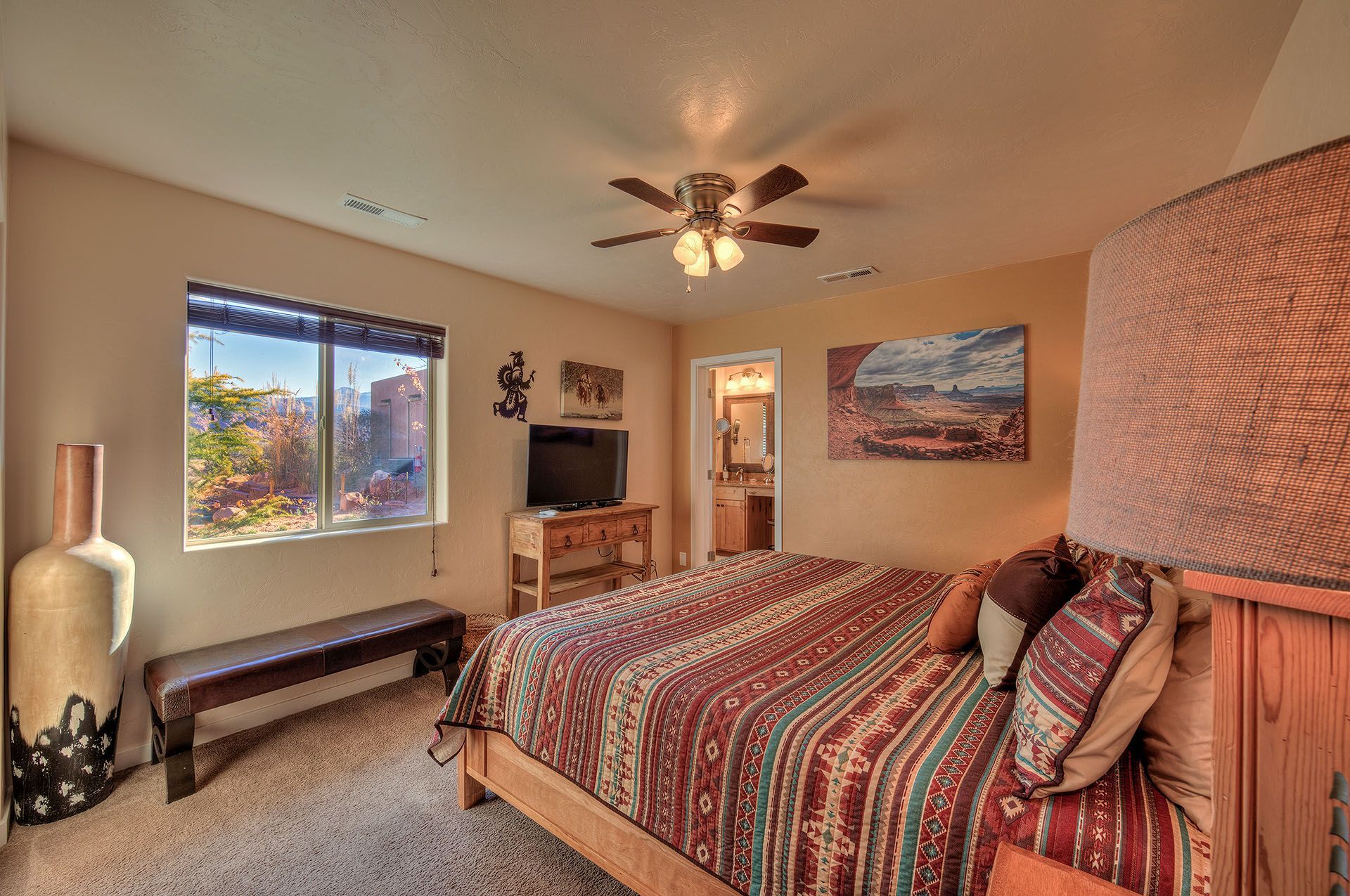 Moab, Utah Oleander Place vacation rental Bedroom with bed, television, window, and decorative art. Earth-toned