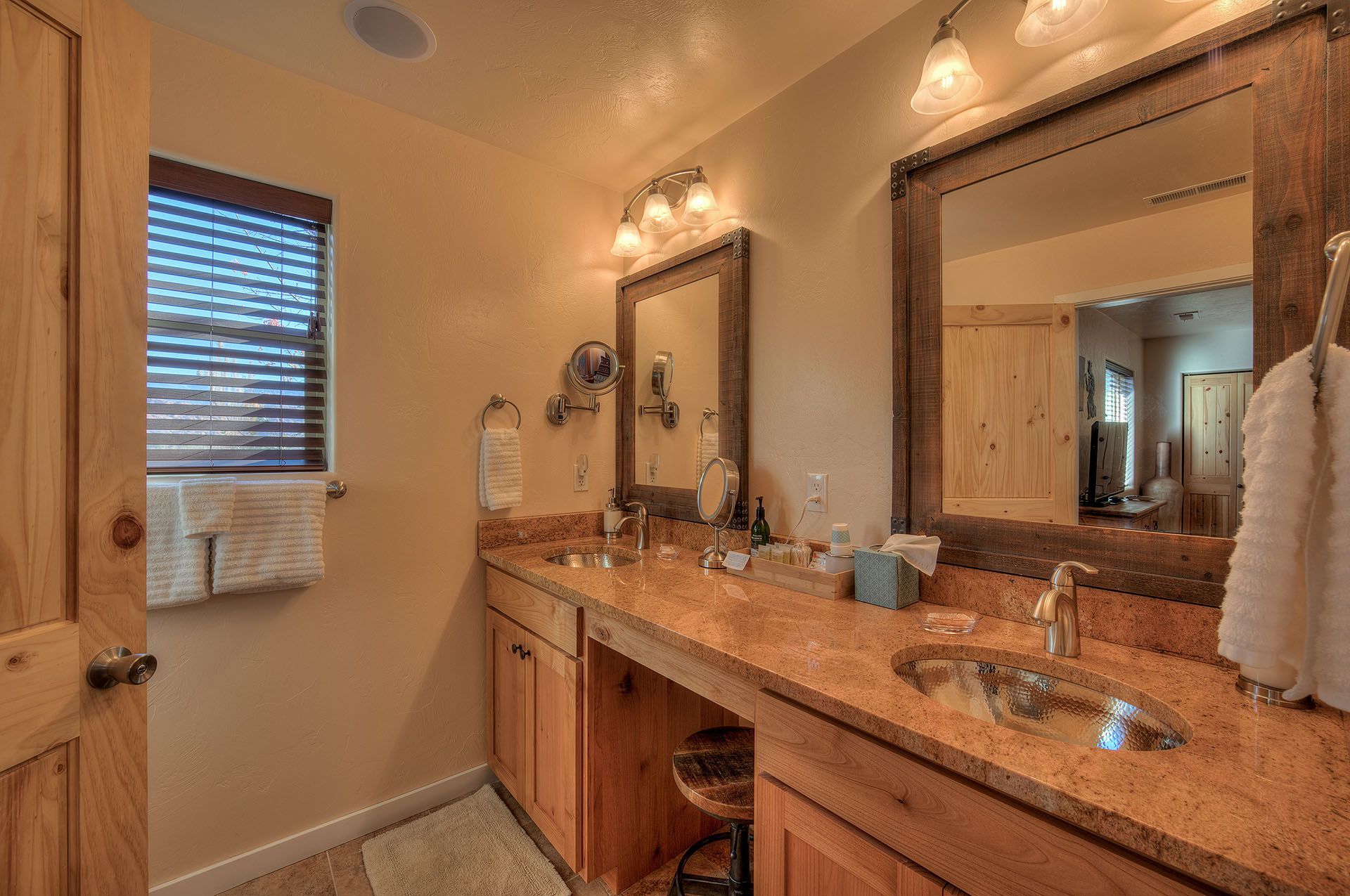 Moab, Utah Oleander Place vacation rental Bathroom with two sinks, wood cabinets, and large mirrors in a rustic style.
