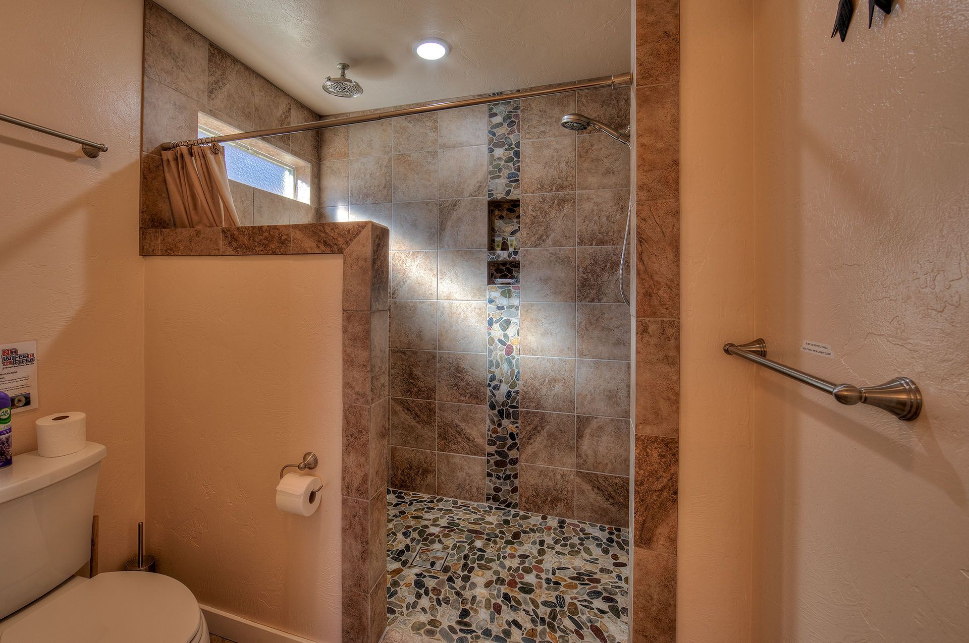 Moab, Utah Oleander Place vacation rental Bathroom with walk-in shower, brown and tan tile, stone floor and towel racks.