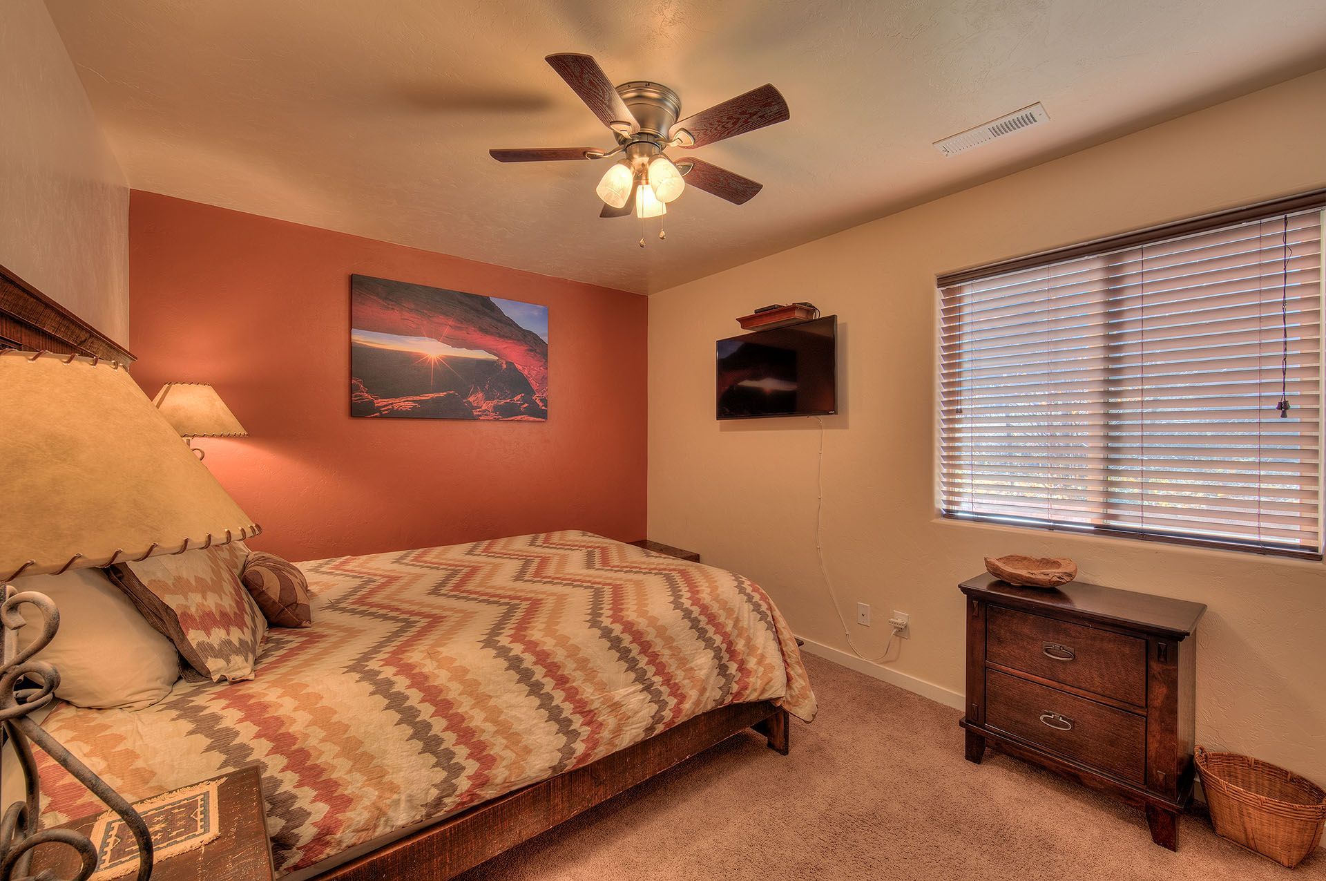 Moab, Utah Oleander Place vacation rental Bedroom with bed, dresser, TV, and artwork on the walls.