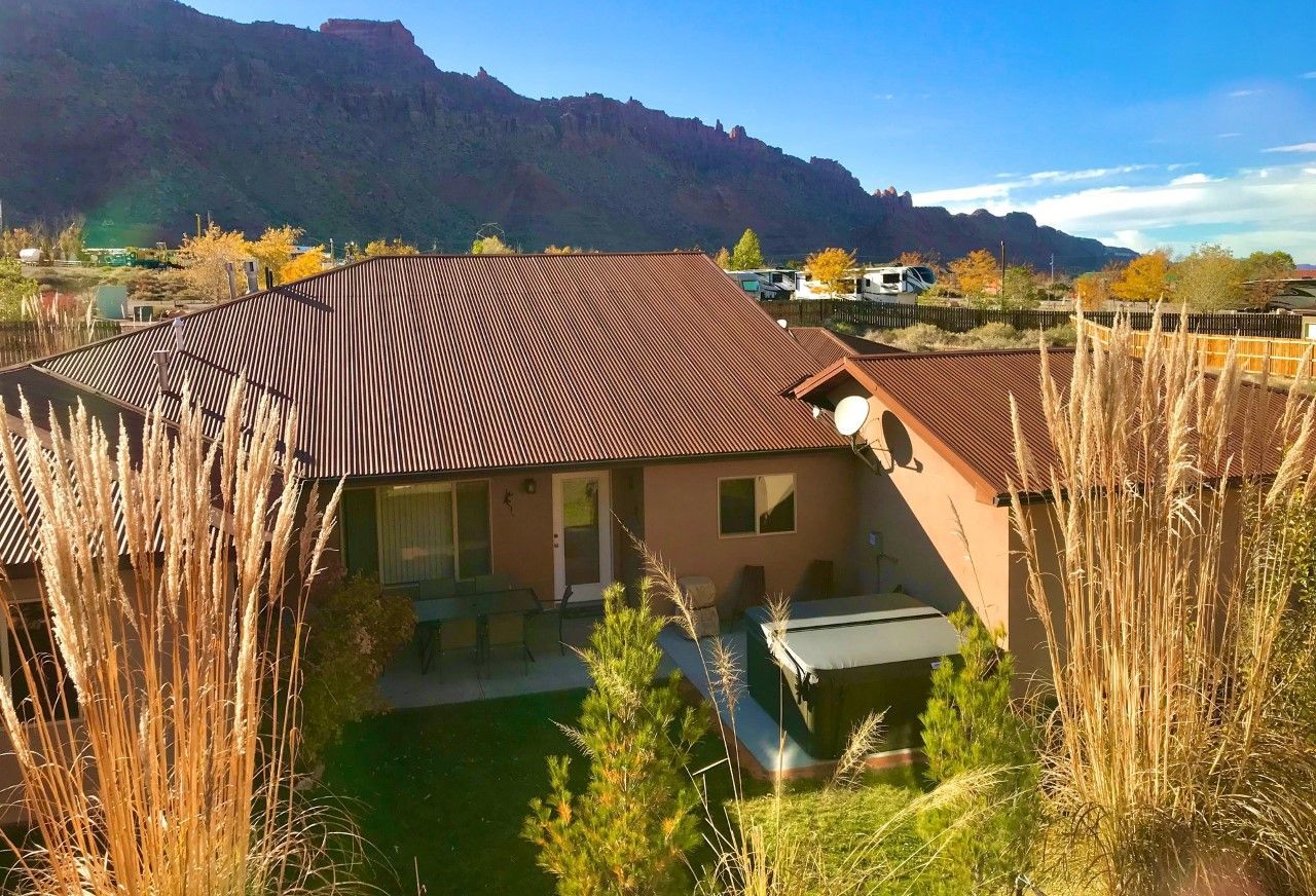 Village Place Moab vacation rental House with brown roof, front yard, and mountain backdrop.
