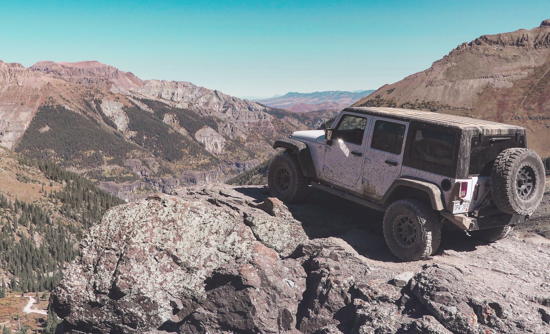 A white jeep is parked on top of a rocky mountain.