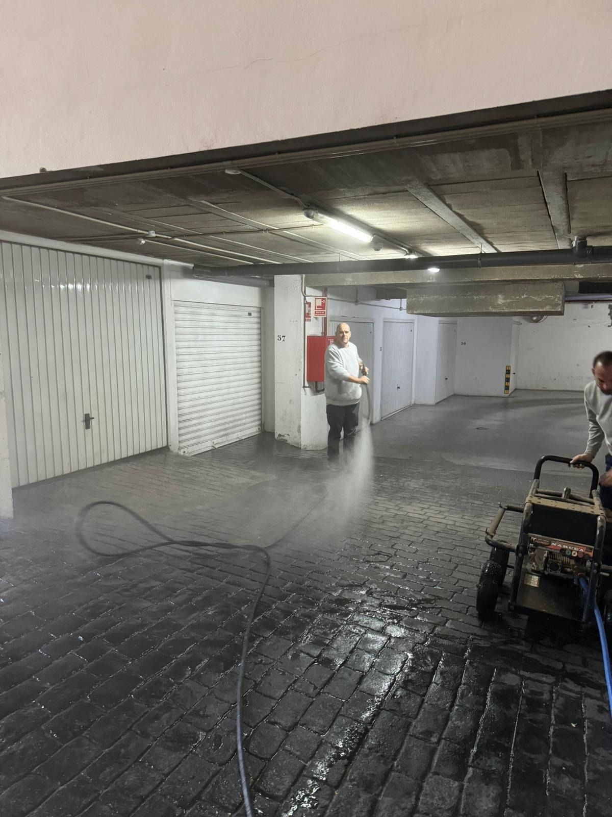 Un hombre está usando una máquina para limpiar el piso de un estacionamiento.