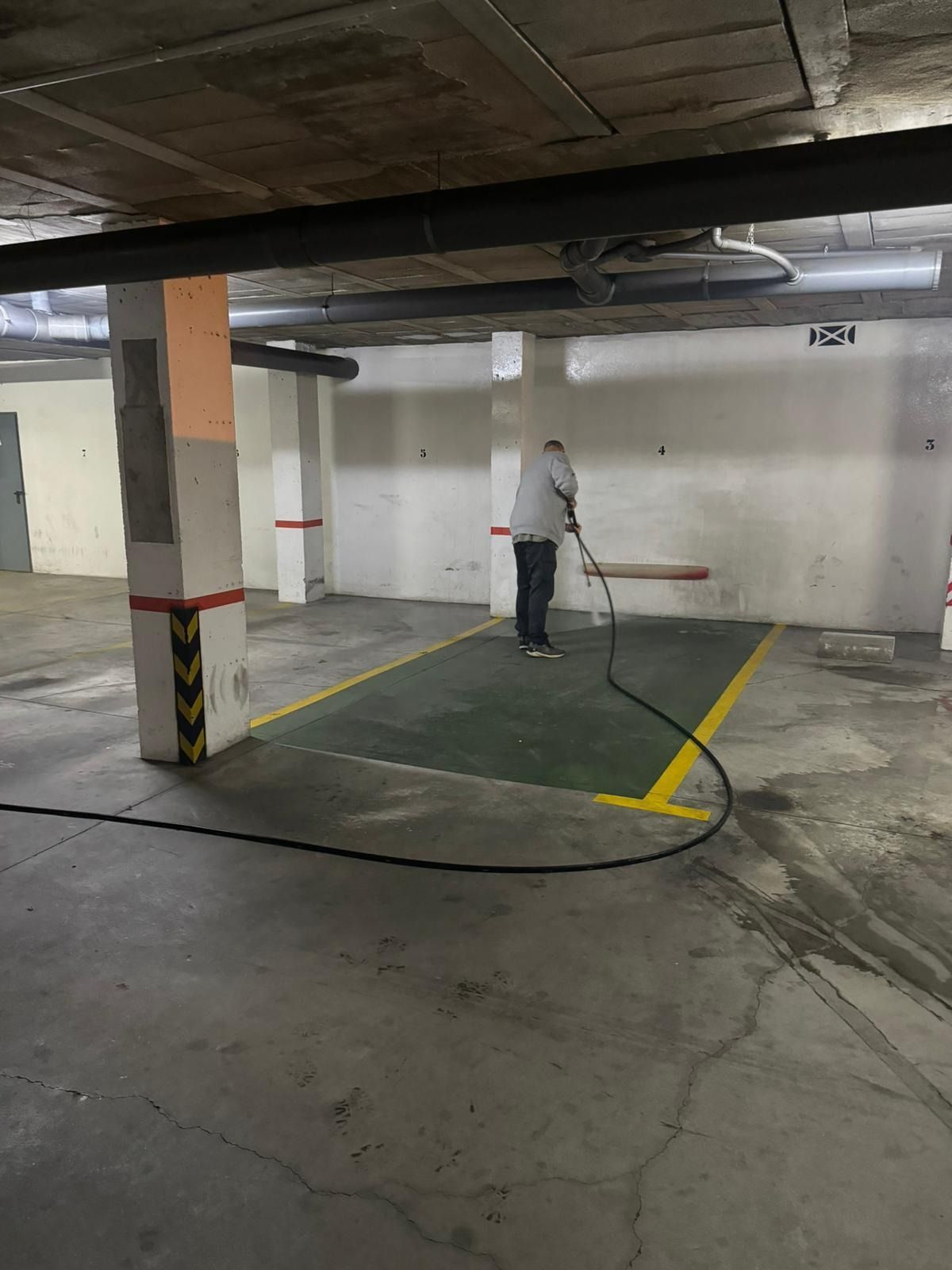 Un hombre está limpiando un estacionamiento con una aspiradora.