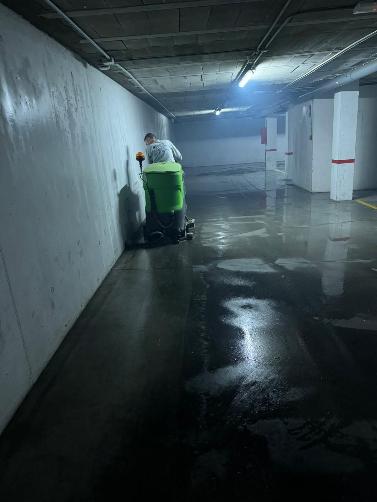Un hombre está limpiando un estacionamiento con una máquina verde.