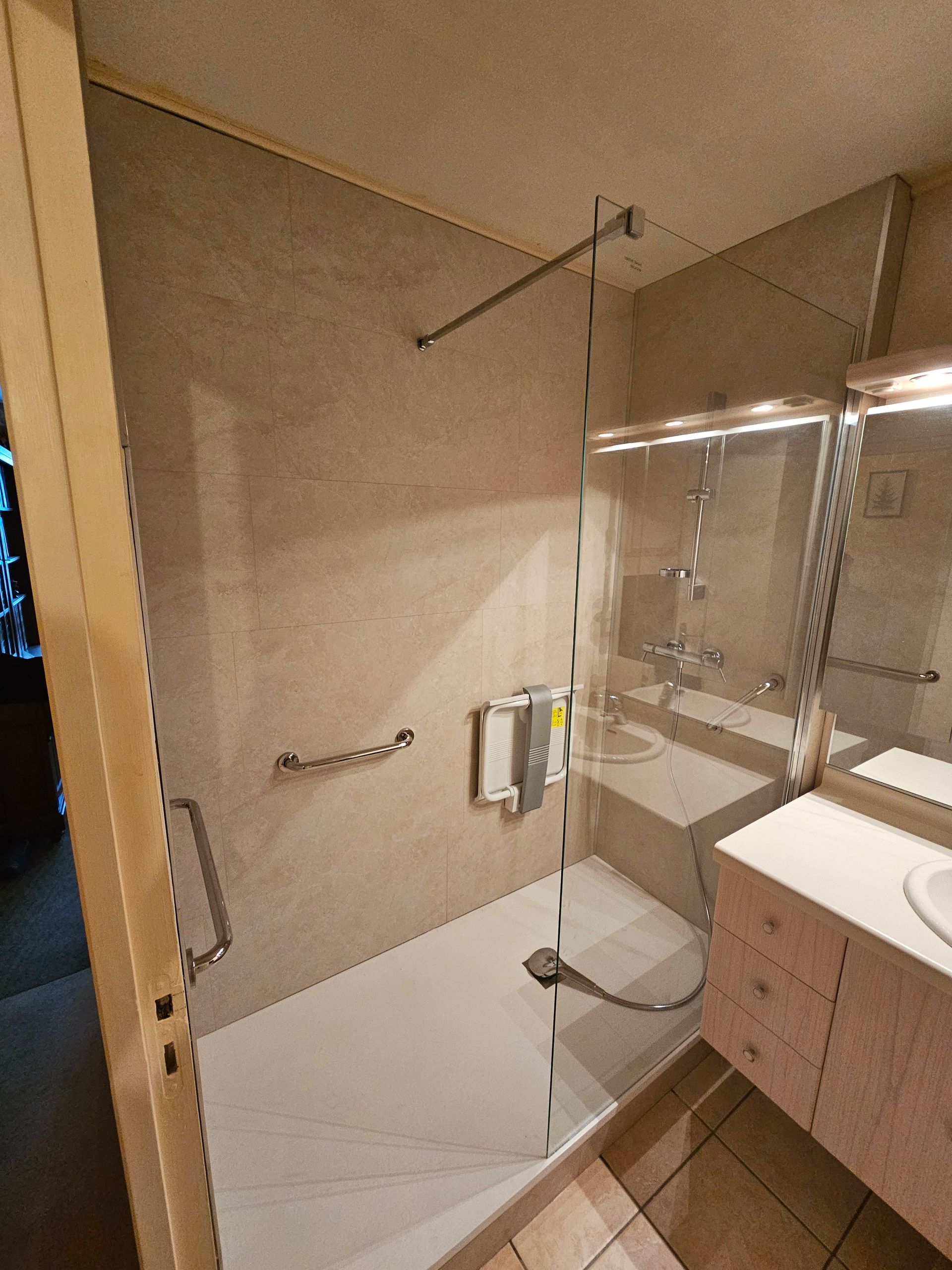 Salle de bains PMR avec barre de maintien, siège de douche rabattable et receveur extra-plat