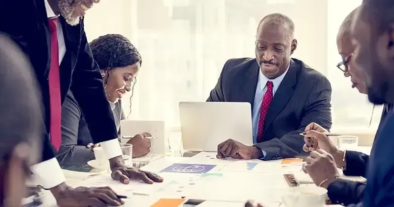 Um grupo de empresários estão sentados ao redor de uma mesa tendo uma reunião.