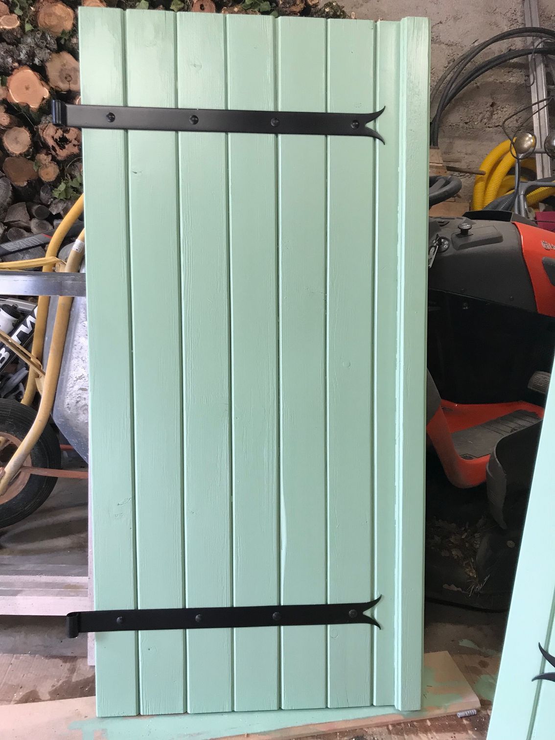 Portail en bois vert clair avec charnières noires.