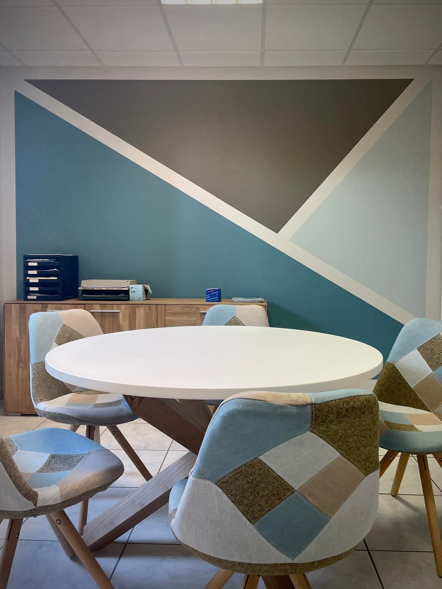 Une pièce avec un radiateur, un tableau, une lampe et une armoire en bois contre un mur beige.