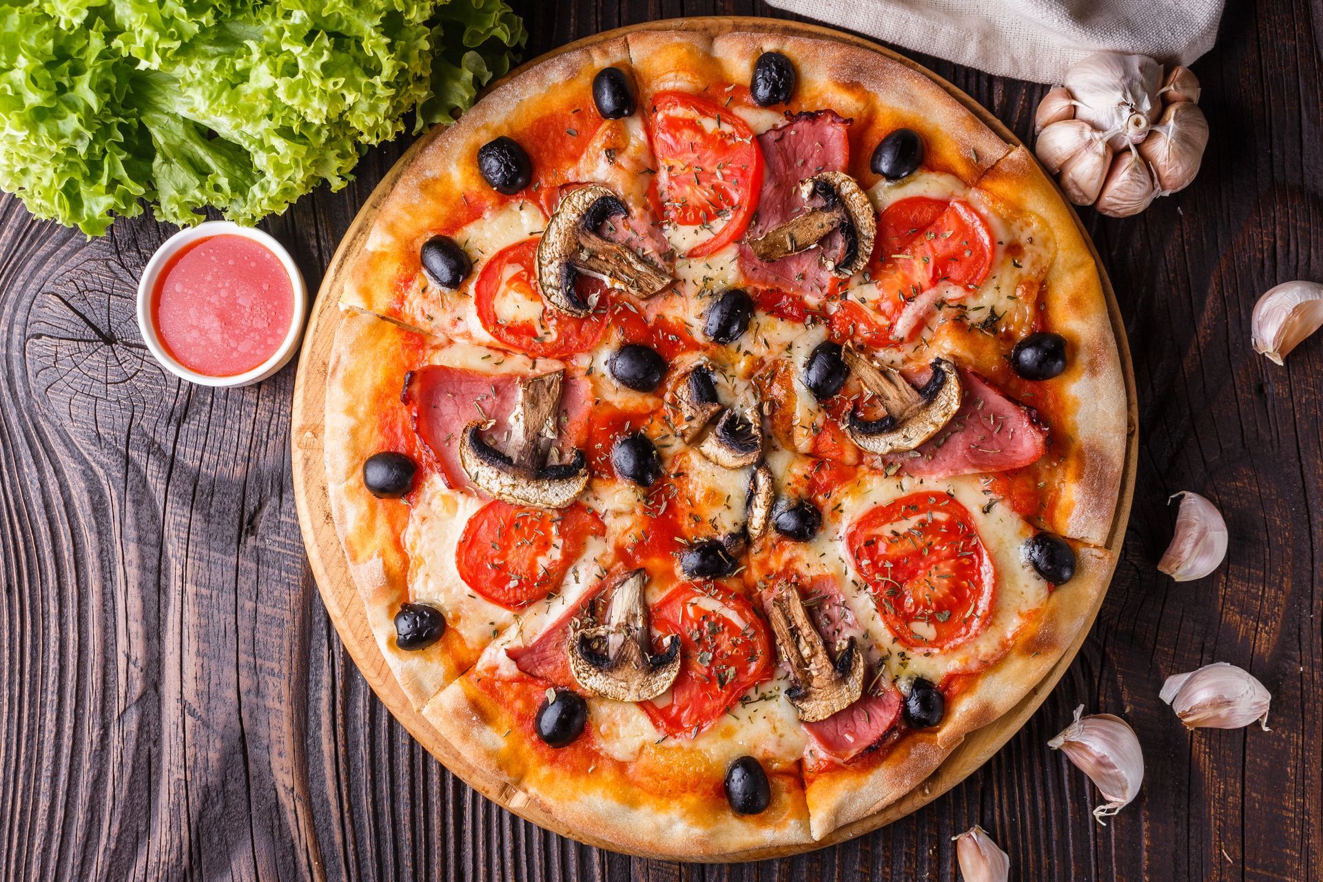 Pizzeria Don Giuseppe - Frisch gebackene Pizza mit Tomaten, Oliven, Schinken und Pilzen