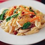 Un plato blanco cubierto con pasta y verduras sobre una mesa.