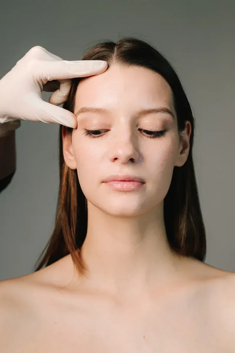 Evaluaci&oacute;n facial est&eacute;tica con guantes m&eacute;dicos, analizando la piel y la zona del contorno de ojos antes de un tratamiento.