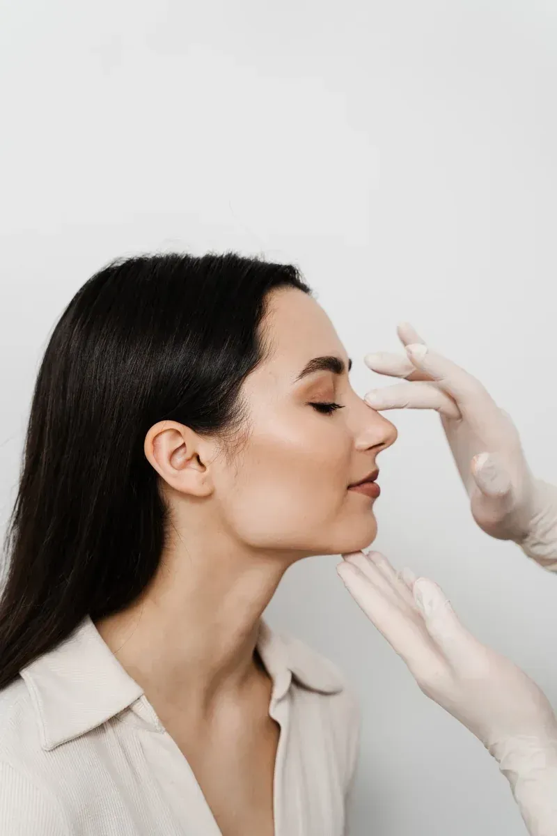 Valoraci&oacute;n est&eacute;tica facial de perfil realizada por un profesional, examinando el rostro antes de un tratamiento m&eacute;dico-est&eacute;tico.