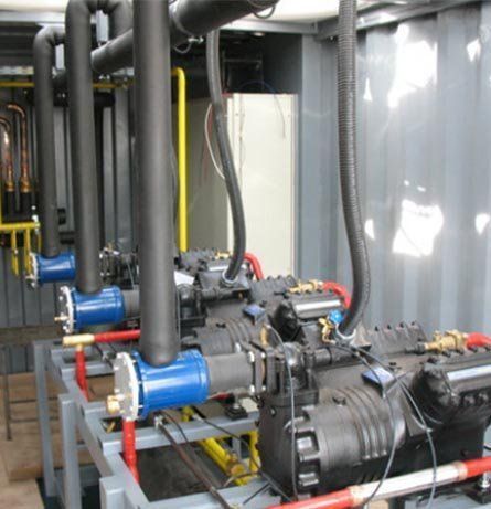 Compresores de refrigeración en carcasa metálica; equipos de color negro y azul con varias tuberías.