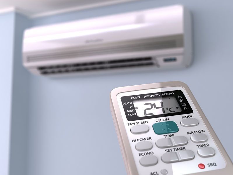 Aire acondicionado con mando a distancia ajustado a 24°C en una habitación de color azul claro.