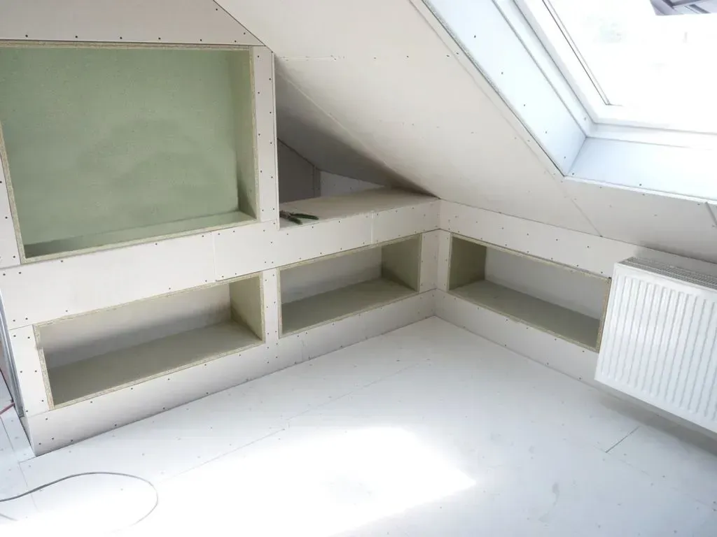 Ein im Bau befindlicher Raum mit Regalen und einem Schrägfenster