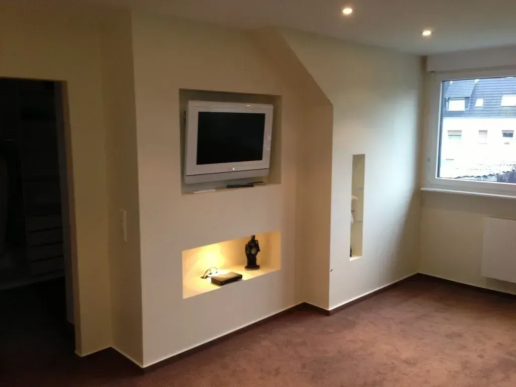 Ein Wohnzimmer mit einem in der Wand montierten Flachbildfernseher