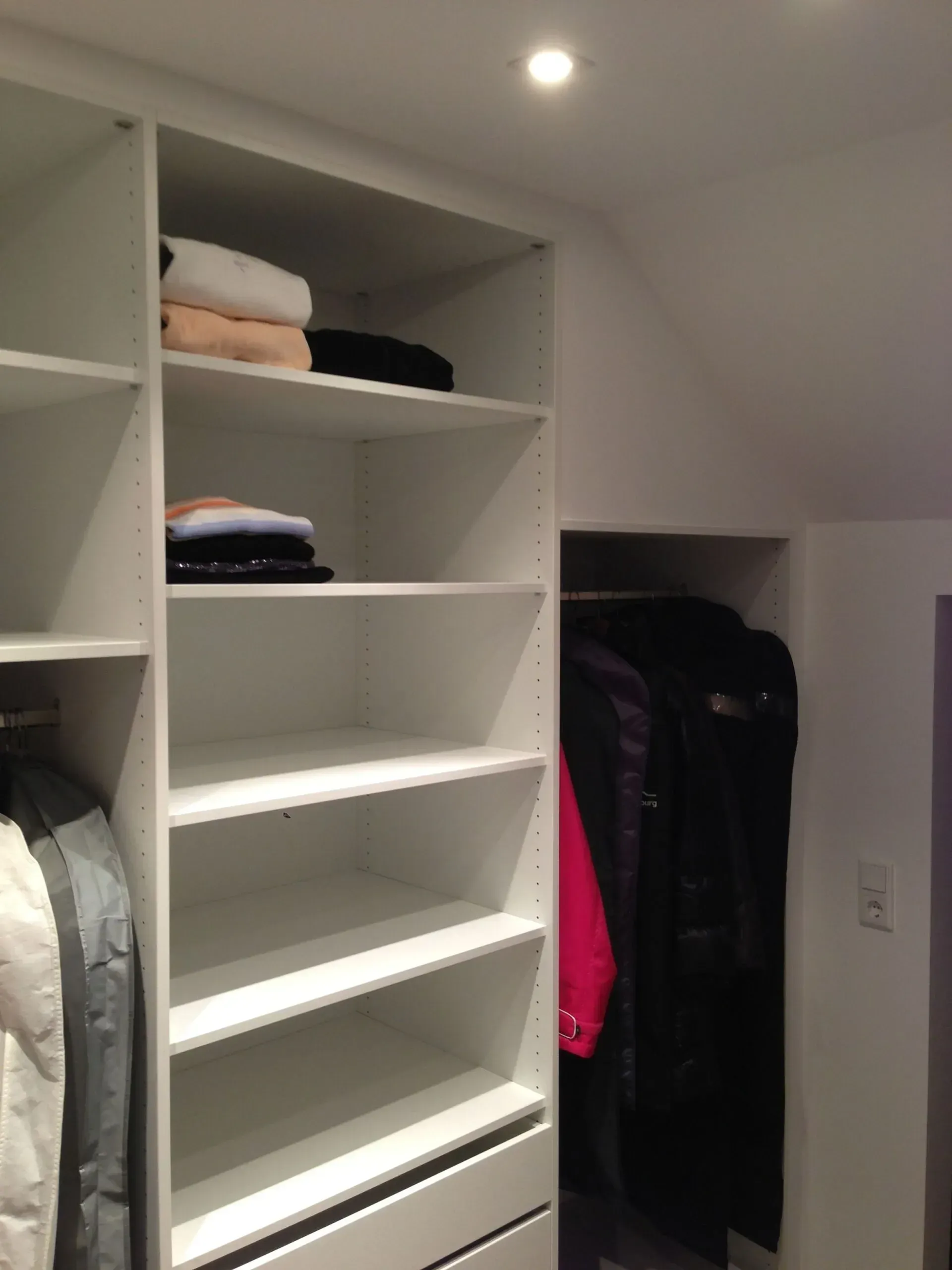 Ein begehbarer Kleiderschrank mit Regalen und Schubladen voller Kleidung