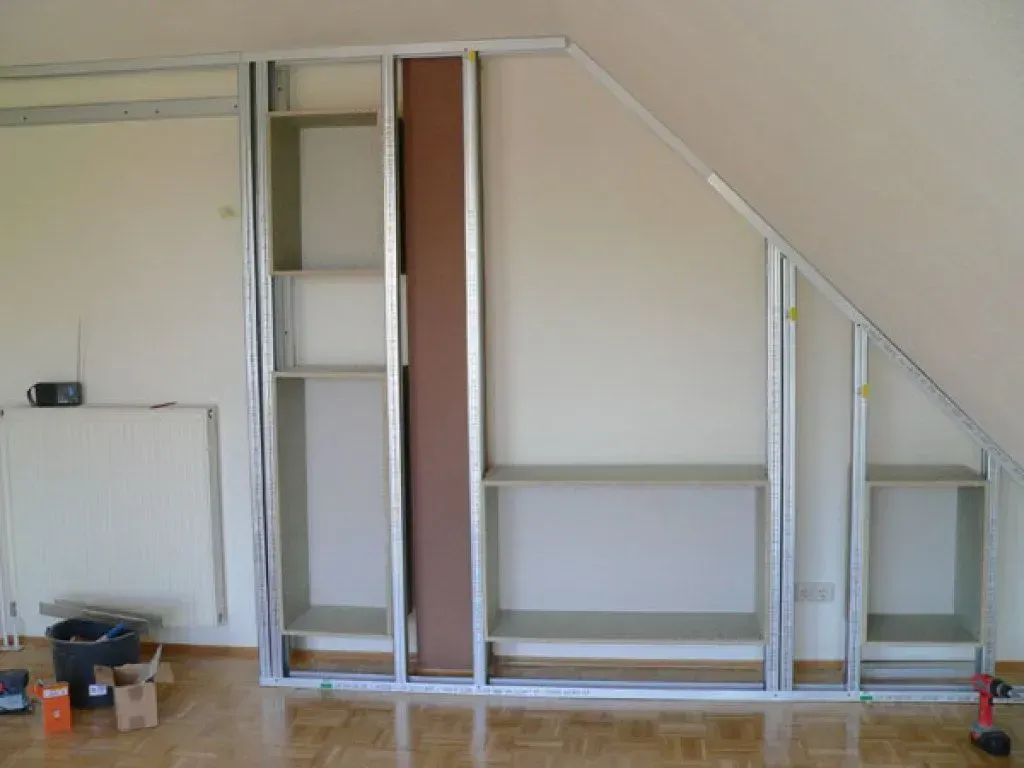 Ein Raum mit einer schrägen Wand und Regalen darunter