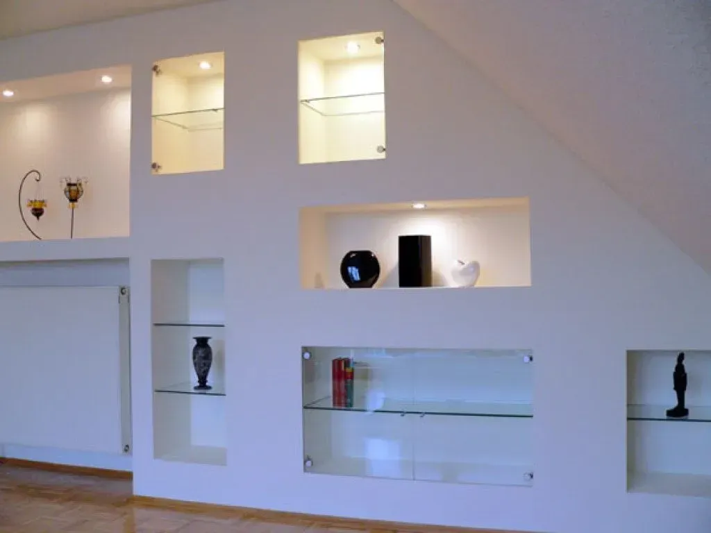 Eine weiße Wand mit Glasregalen und Vasen darauf