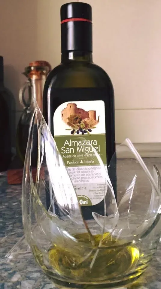 Una botella de aceite de oliva Almazara San Miguel reposa detrás de un cuenco 