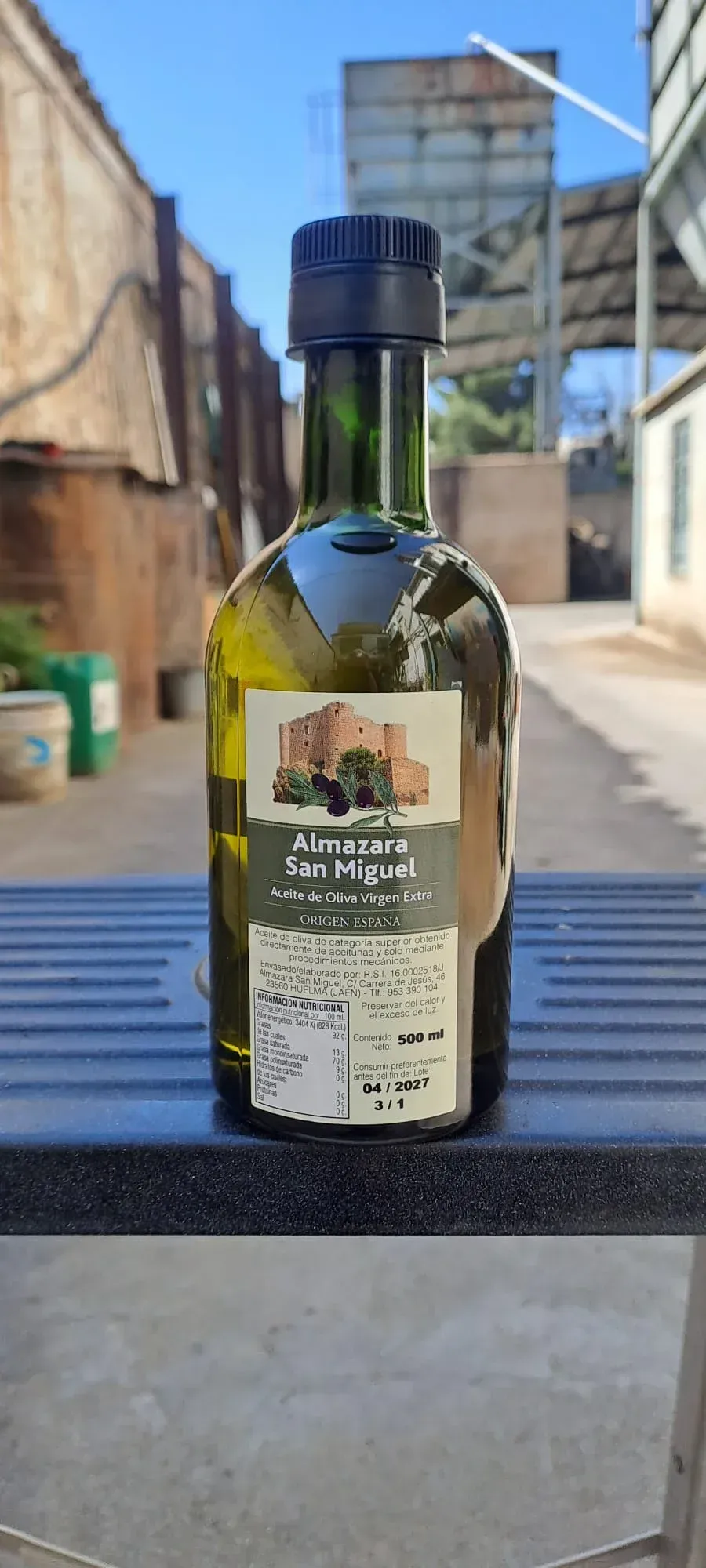 Una botella de aceite de oliva virgen extra con una etiqueta que muestra un edificio