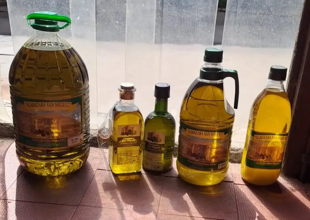 Cinco botellas de aceite de oliva de diferentes tamaños, alineadas sobre una superficie