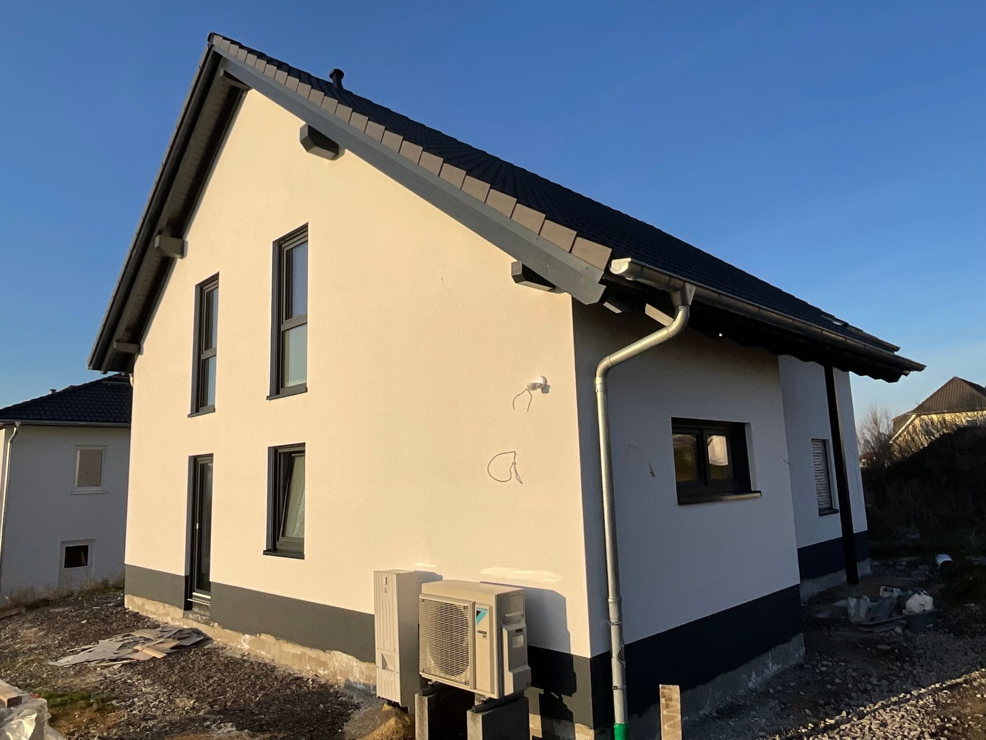 Eine Reihe farbenfroher Stadthäuser mit Solarpaneelen auf dem Dach unter blauem Himmel.
