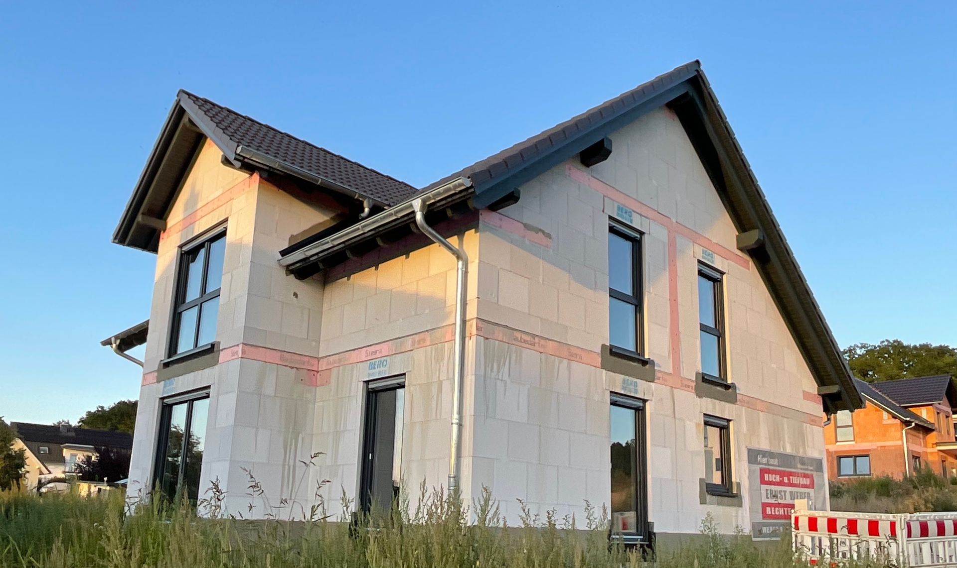 Eine Reihe von Stadthäusern, jedes in einer anderen Farbe: grün, orange und rot, mit Holzelementen.