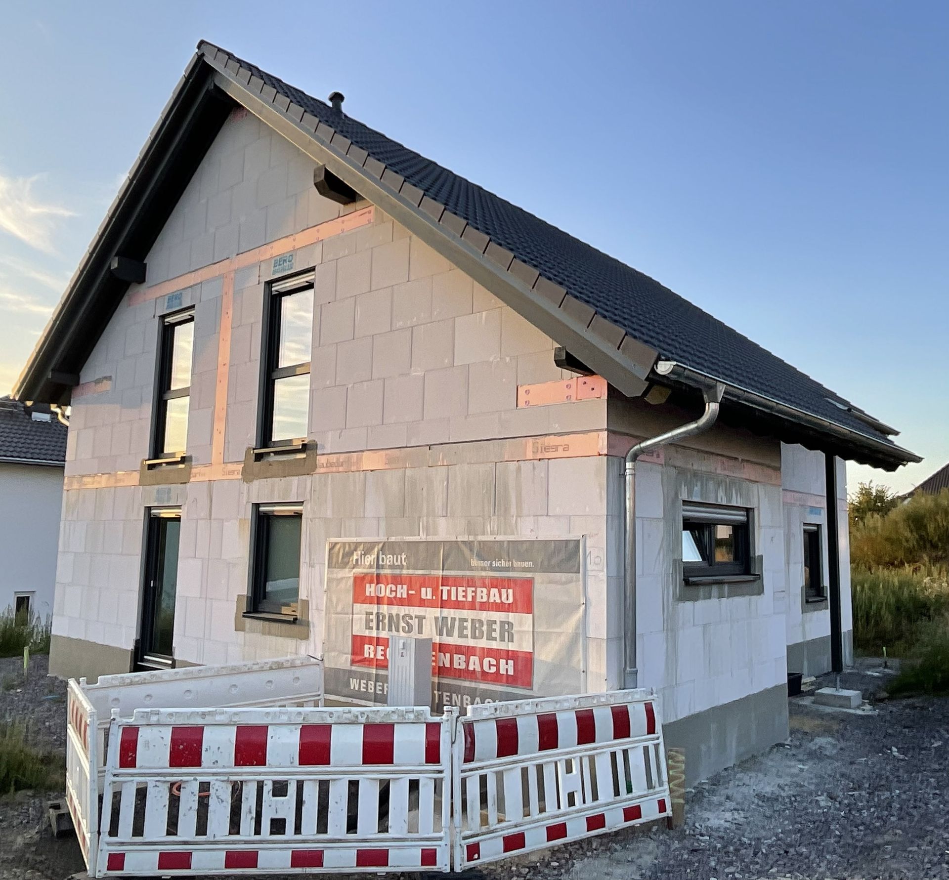 Eine Reihe farbenfroher Reihenhäuser mit Solarpaneelen auf dem Dach und passenden Schuppen in den Vorgärten.