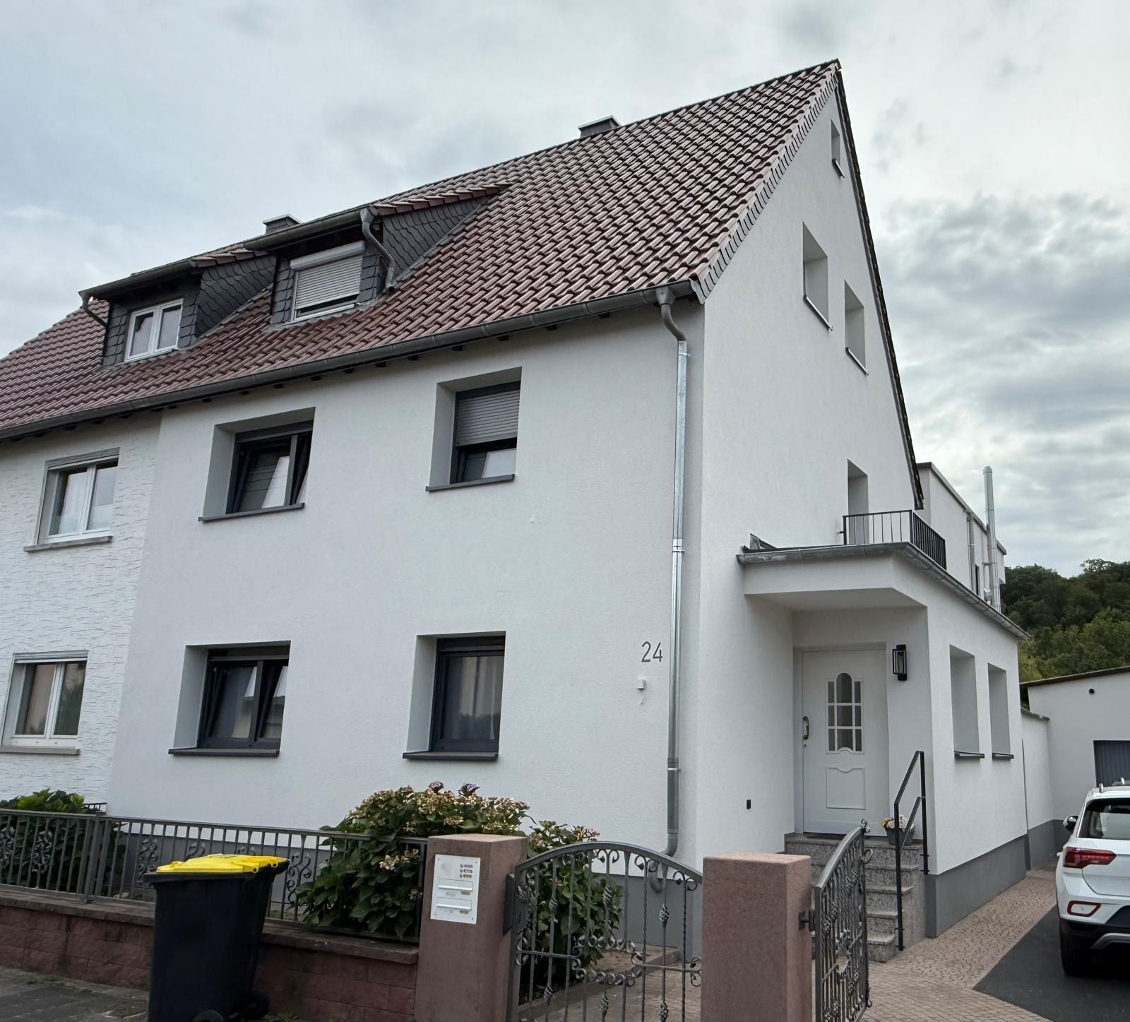 Eine Reihe farbenfroher Reihenhäuser mit Solarpaneelen auf dem Dach und passenden Schuppen in den Vorgärten.