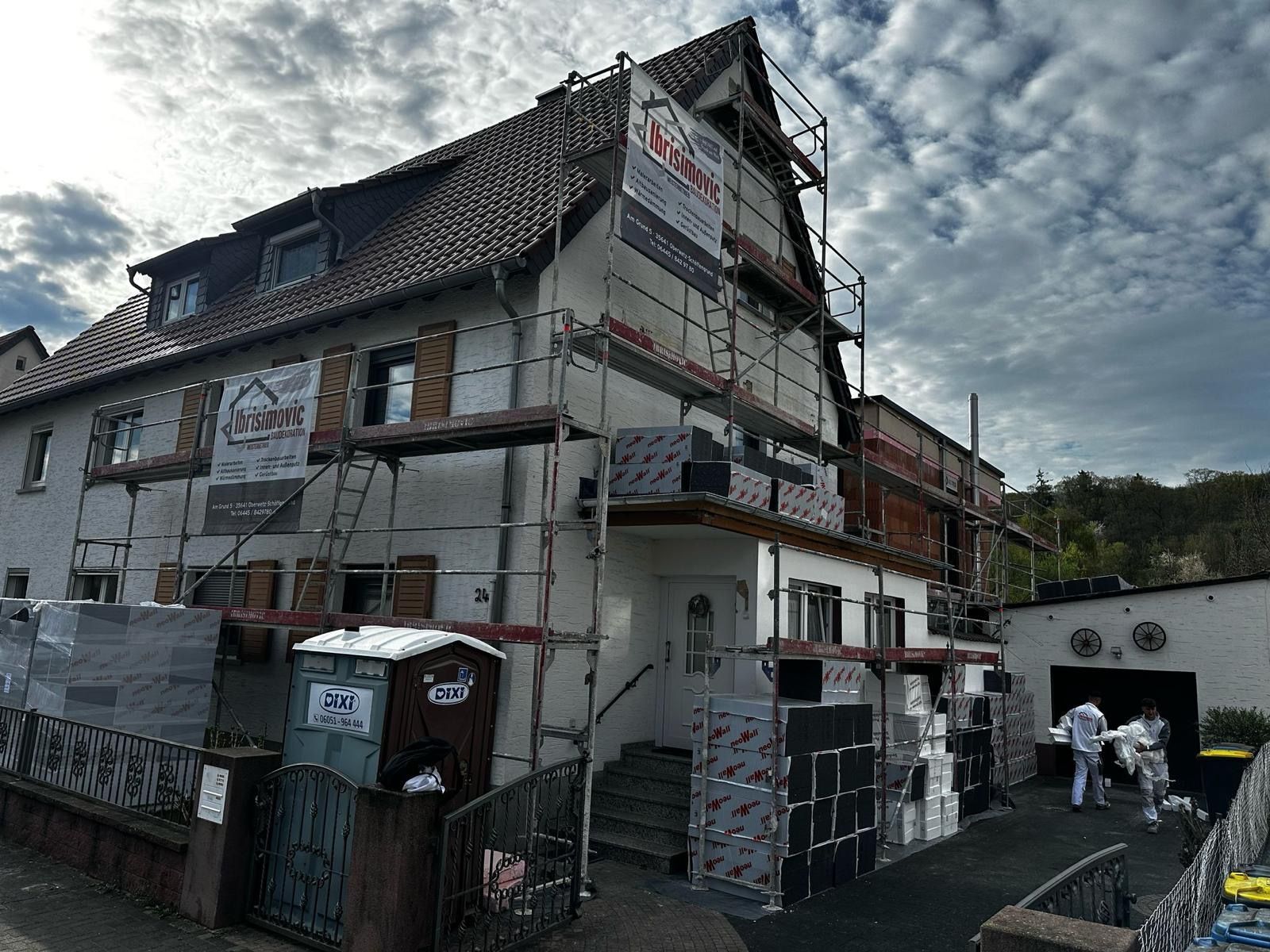 Eine Reihe von Stadthäusern, jedes in einer anderen Farbe: grün, orange und rot, mit Holzelementen.