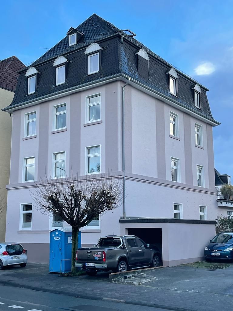 Eine Reihe von Stadthäusern, jedes in einer anderen Farbe: grün, orange und rot, mit Holzelementen.