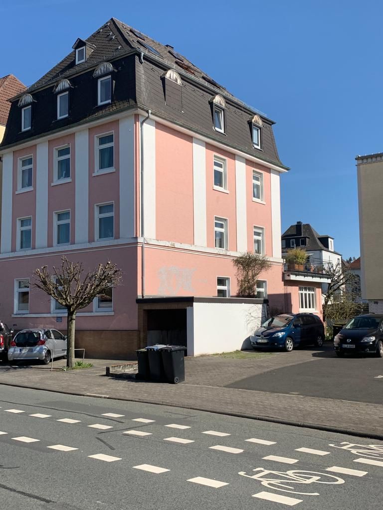 Eine Reihe bunter Stadthäuser mit Holzzäunen unter blauem Himmel.