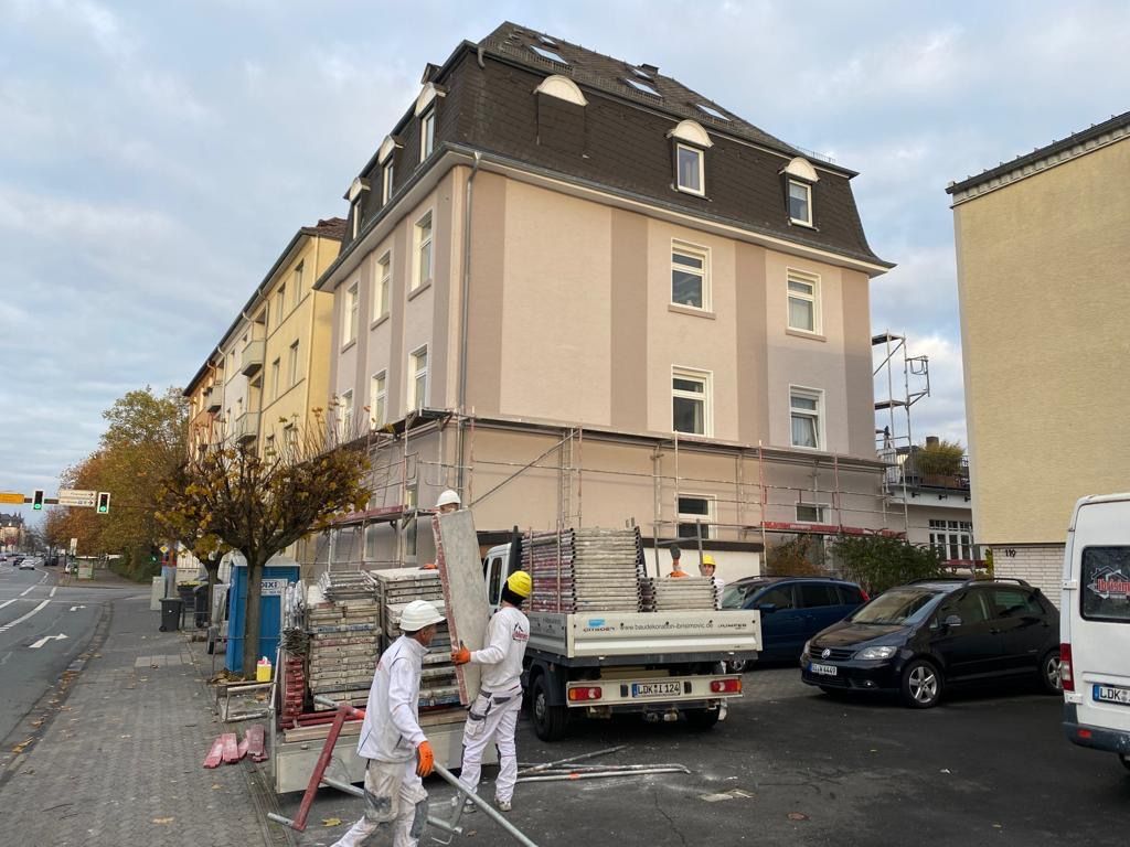 Eine Reihe farbenfroher Stadthäuser mit Solarpaneelen auf dem Dach unter blauem Himmel.