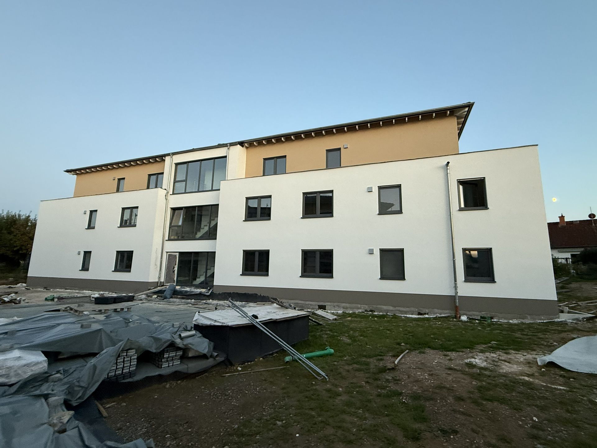 Eine Reihe farbenfroher Stadthäuser mit Solarpaneelen auf dem Dach unter blauem Himmel.