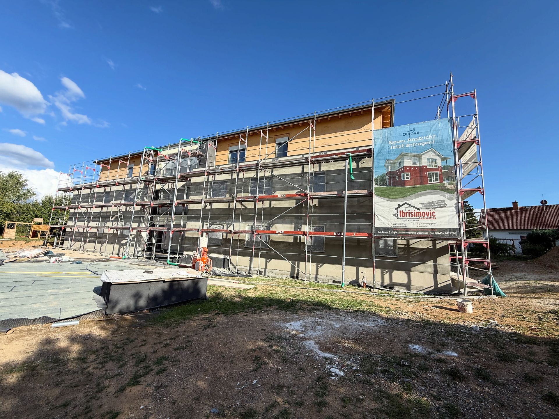 Eine Reihe farbenfroher Reihenhäuser mit Solarpaneelen auf dem Dach und passenden Schuppen in den Vorgärten.