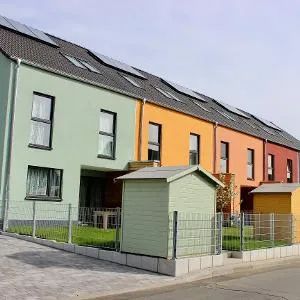 Eine Reihe farbenfroher Reihenhäuser mit Solarpaneelen auf dem Dach und passenden Schuppen in den Vorgärten.